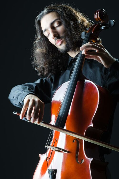 Violoncelliste masculin jouant du violoncelle sur fond sombre